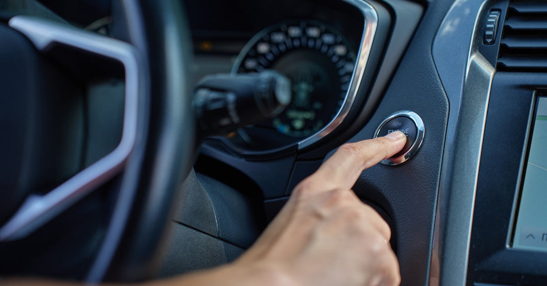 A close-up of a hand pressing the start button to turn on the car engine. It's a keyless ignition system in a modern car.