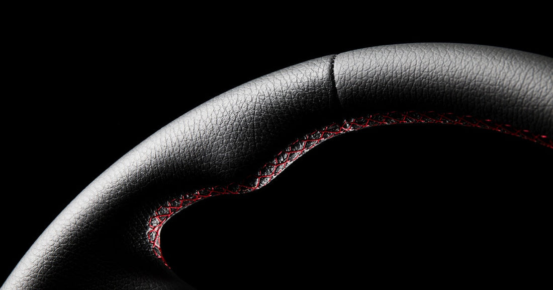 A close-up of a freshly repaired leather steering wheel with a black background and studio red lighting.